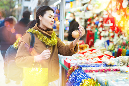 Portrait of smiling happy woman holding christmas ball in her hands on street marketの写真素材