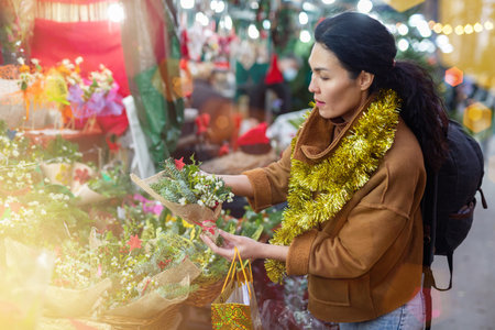 Asian female purchasing christmas bouquet at fairの写真素材
