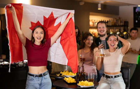 Excited canadian fans cheer for their team as they watch the match on TV in beer barの写真素材