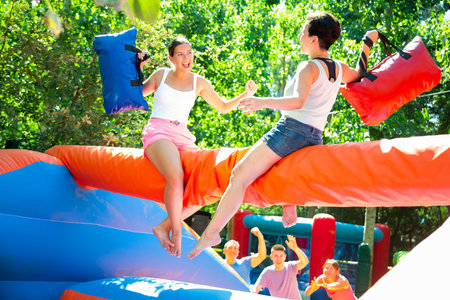 Cheerful young women having fun on inflatable pillow fight arena