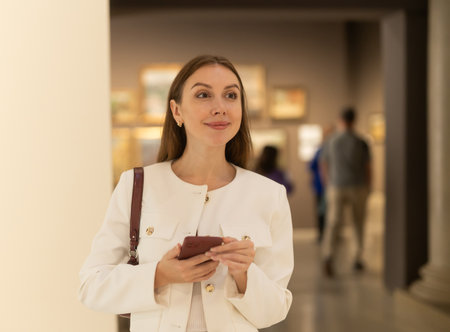While visiting museum, girl uses travel guide application on her phone.の写真素材