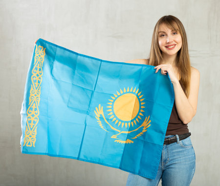 Joyful female fan of favorite team of Kazakhstan with the national flag in her handsの写真素材