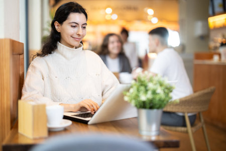 Young woman with laptop drinking coffeeの写真素材