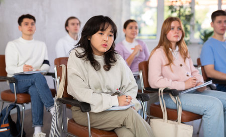 High school students sit at their desks and listen carefully to the teacher at lesson at schoolの写真素材
