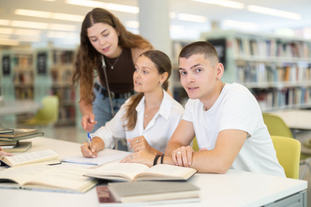 Group of students reading books and taking notes in libraryの写真素材