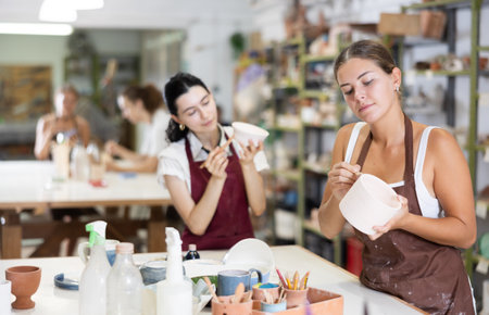 Girl performs polishing of ceramic productの写真素材