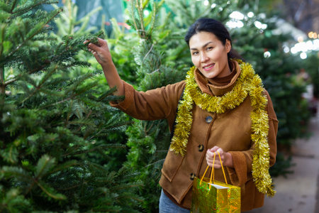 Happy asian woman chooses Christmas tree on street marketの写真素材