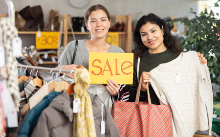 Latin girl and female model with poster in hands announces mega saleの写真素材