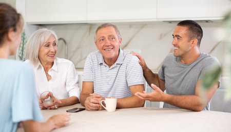 Family of four sits at table and talkingの写真素材