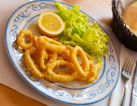 Fried squids in a batter of tempera flour served with saladの写真素材