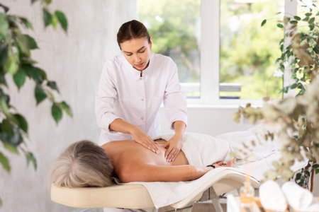 Young woman doing back massage to elderly womanの写真素材