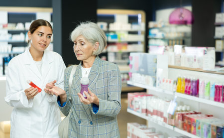 Mature lady choosing lubricant with help of young female pharmacistの写真素材
