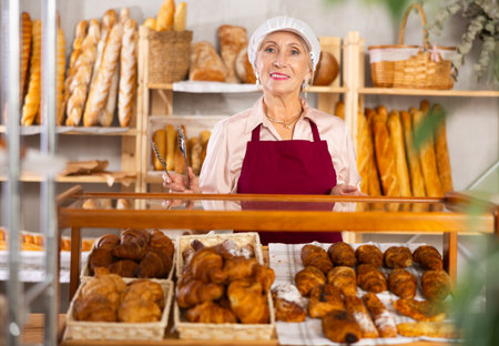 Senior female baker holds basket with finished productsの写真素材