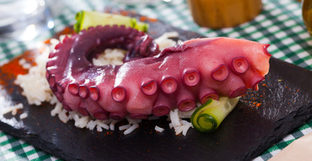Octopus tentacles served with rice on a wooden boardの写真素材