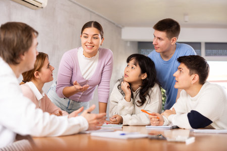 Young teacher discussing her notes with students around the tableの写真素材