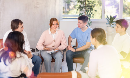 Smiling young female team leader holding meeting with fellow studentsの写真素材
