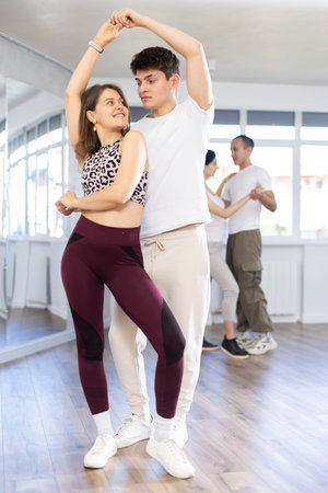 Young couple dancing playful bachata during group class
