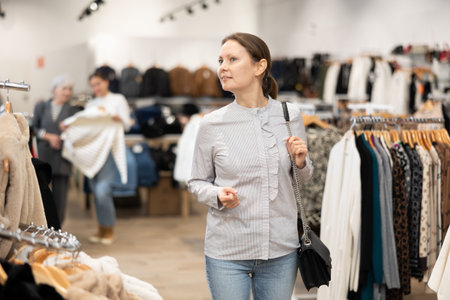 Middle-aged woman watching excitedly large stock of clothes in clothing storeの写真素材