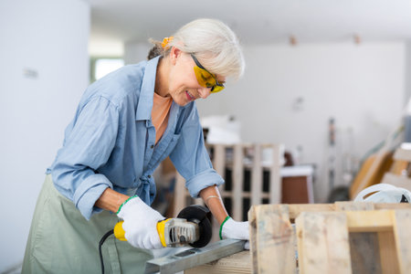 Mature woman renovating home, cutting metal profileの写真素材