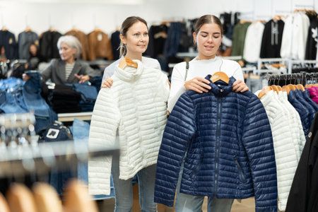 Two women choosing white jacket in clothing storeの写真素材