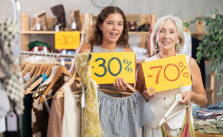 Elderly and young women choose discounted clothes in storeの写真素材