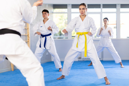 Young woman attendee of karate classes practicing kata standing in row with othersの写真素材