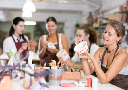 Girl painting with brush on handmade ceramic bowlの写真素材