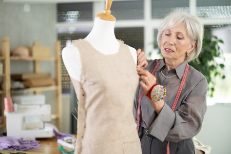 Mature female dressmaker working with mannequin in sewing workshopの写真素材