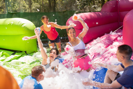 Group of happy men and women swimming in foam poolの写真素材