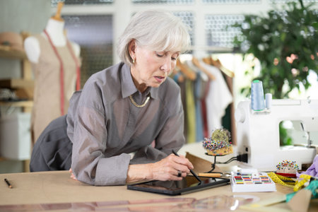 Mature dressmaker drawing sketch on tabletの写真素材