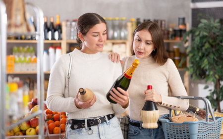 Two friends choose and buy wine together the grocery department of supermarketの写真素材