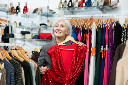 Elderly woman choosing dress in storeの写真素材
