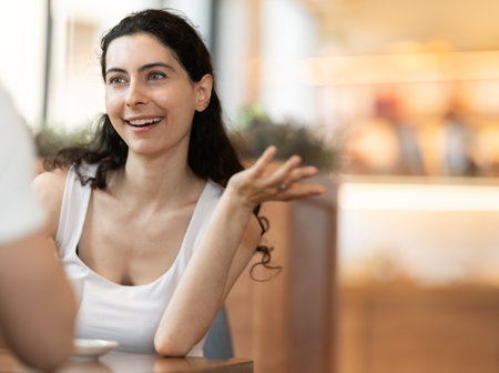 Young woman drinking with her friend in cafeの写真素材