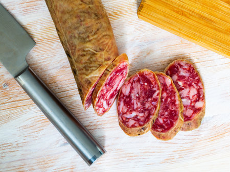 Spanish salchichon sausage cut in slices on a wooden surfaceの写真素材