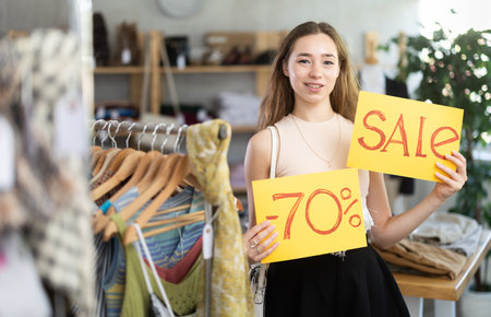 Young woman holding discount sign in clothing storeの写真素材