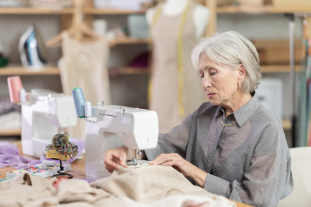 woman dressmaker sews on a machine in a workshopの写真素材