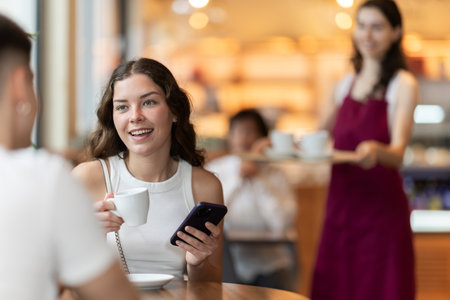 Couple young man and woman with phone in cafeの写真素材