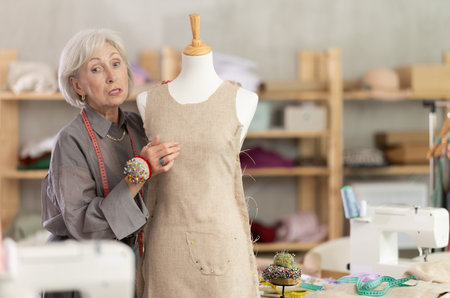 Woman seamstress adjusts clothes on mannequinの写真素材