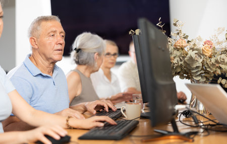 Concentrated elderly man immersed in using computerの写真素材