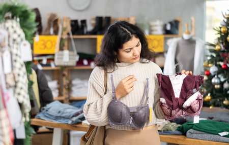 Latina chooses a bra against the background of a Christmas tree in a storeの写真素材