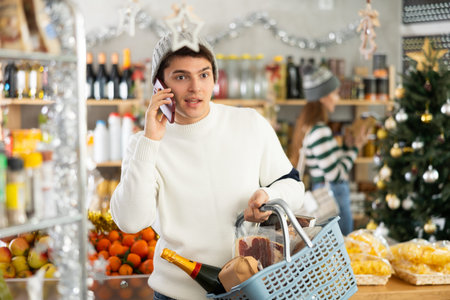 Guy talking on mobile phone - asking for advice on what products to buy at supermarket for Christmas