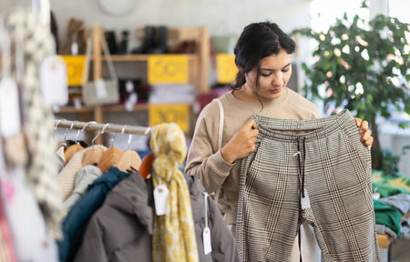 woman looking at pants with belt in clothing storeの写真素材