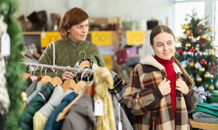Woman chooses jacket and coat for the winter period in fashionable clothing storeの写真素材