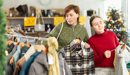 Adult woman and teenage girl choosing coat or down jacketの写真素材