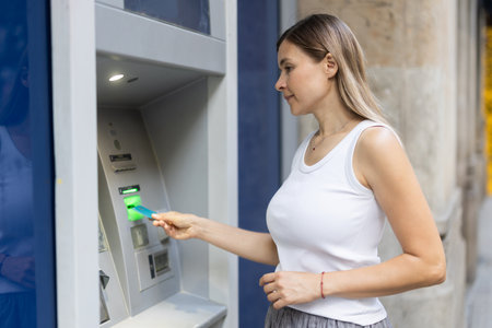 Woman uses outside ATM. Cash withdrawal, user interfaceの写真素材