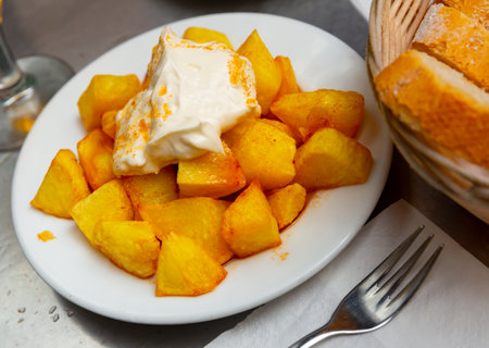 Top view of Patatas bravas, Spanish dish of fried potatoes served with cheese sauce and spicy sauce with paprikaの写真素材