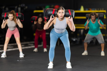 Young woman doing exercises with a bag in the gym