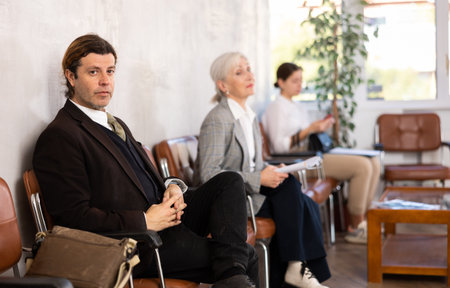 Adult man in suit sitting on chair in the officeの写真素材