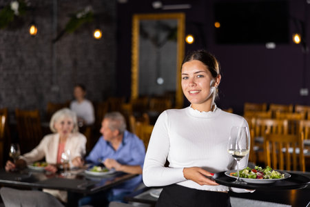 Young woman waiter posing with tray in restaurantの写真素材