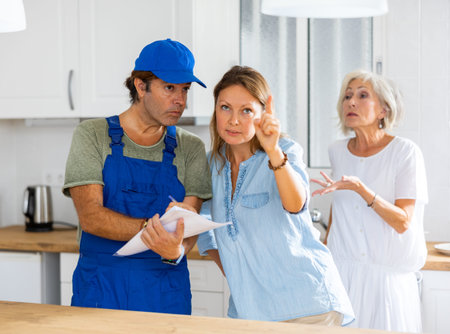 Housewife tells the plumber where to change the pipes in the kitchen